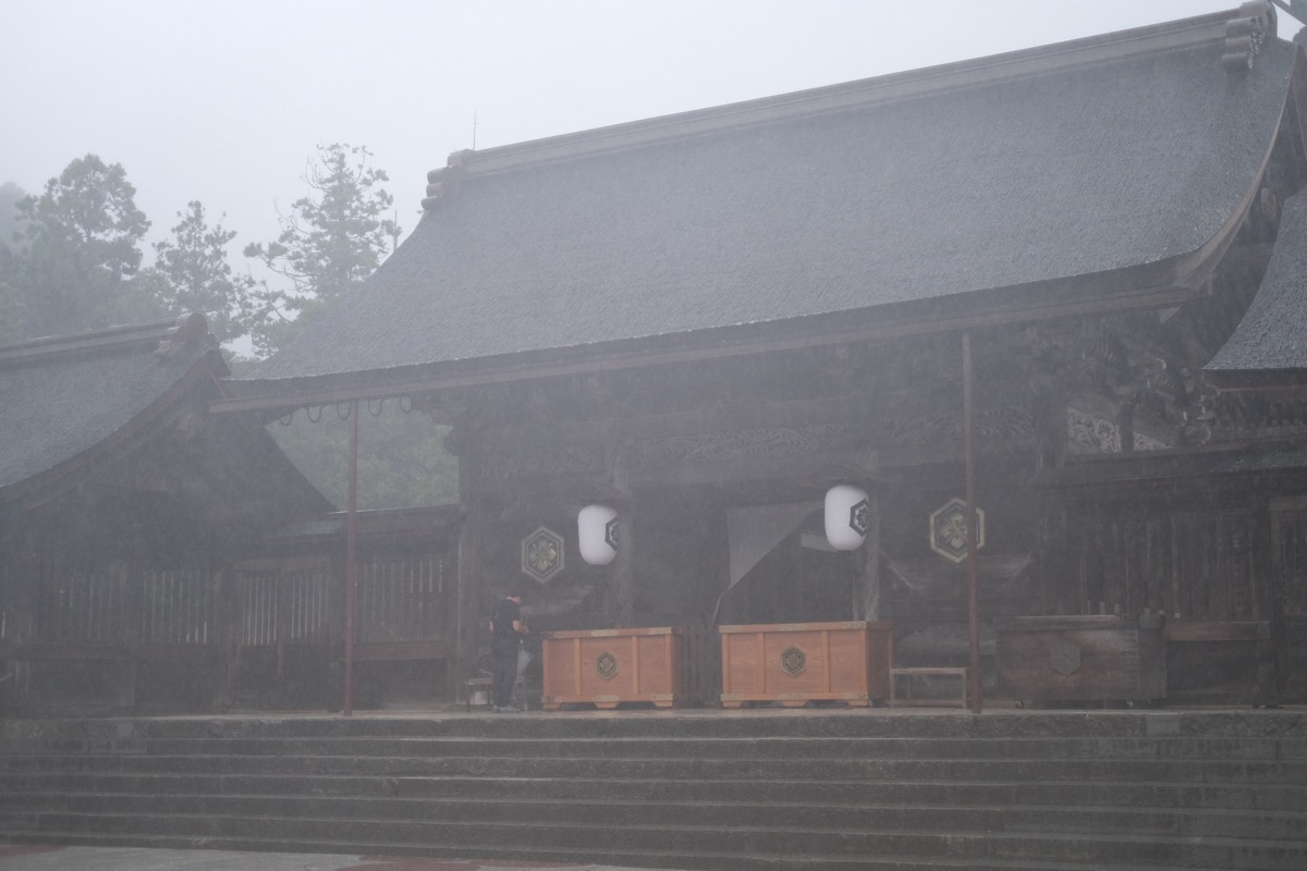 雨で白く霞んだ八足門。輪郭だけがぼんやり見えている