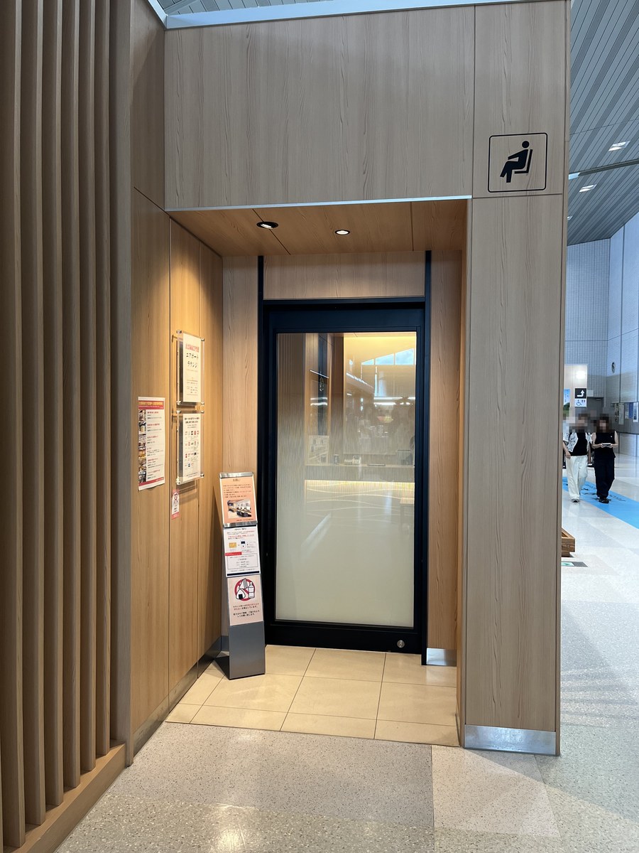 出雲縁結び空港エアポートラウンジの入口。木目の壁とすりガラスの扉、右手に料金の案内看板