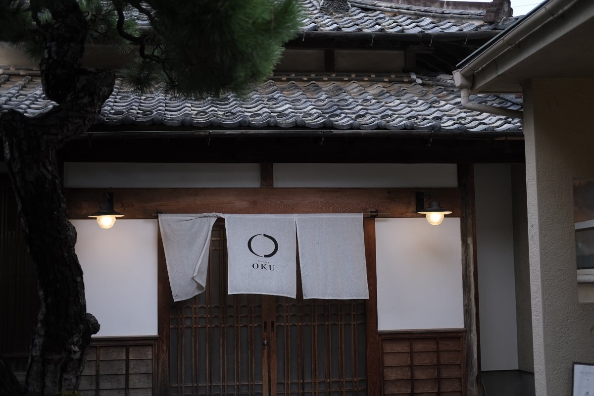宿の玄関にかかる白い暖簾。OKUの文字が入っている