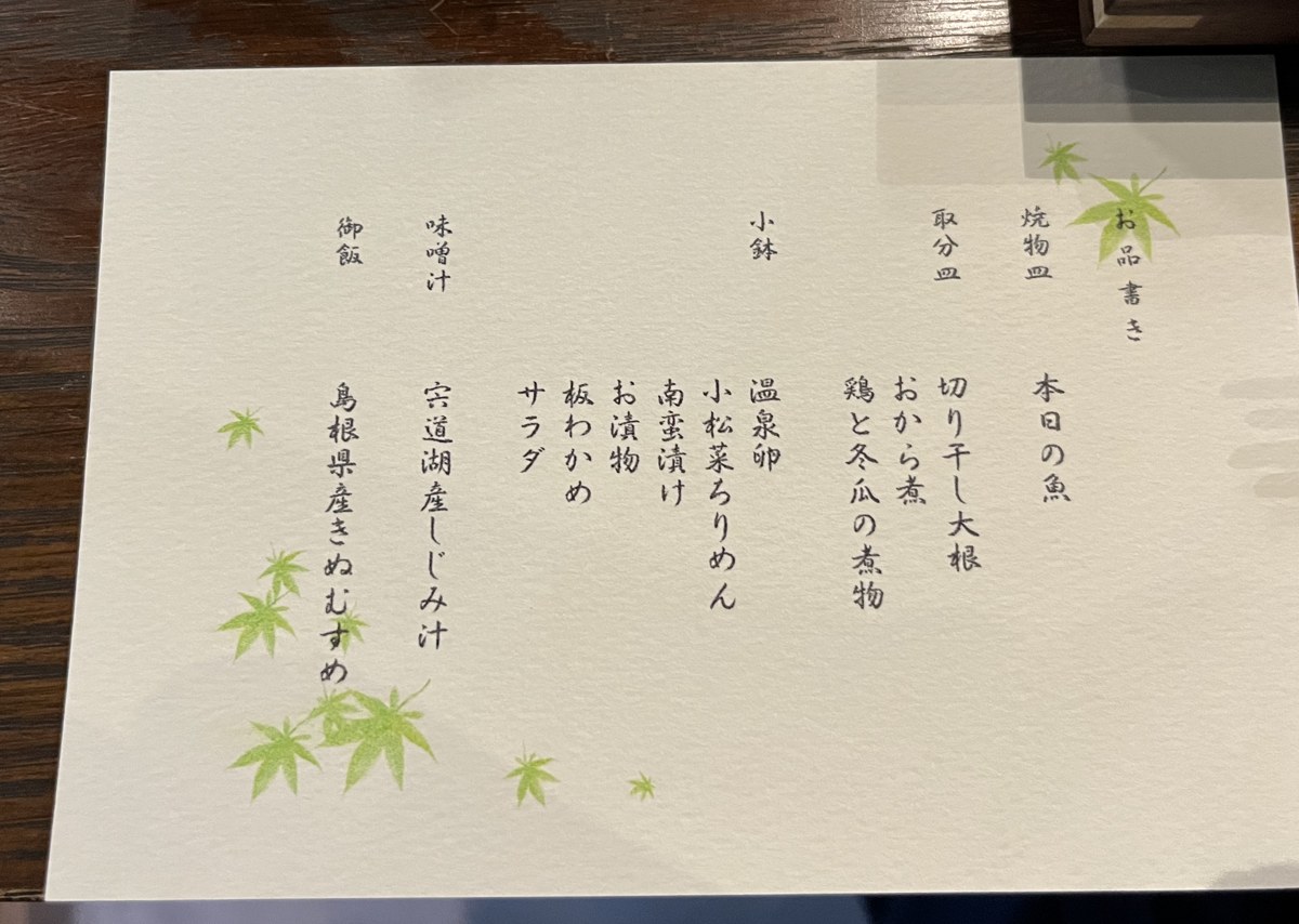 朝食のお品書き。もみじの絵が描かれた和紙に品名が縦書きされている